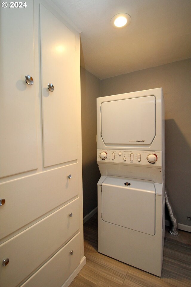 clothes washing area featuring light hardwood / wood-style floors and stacked washer and clothes dryer