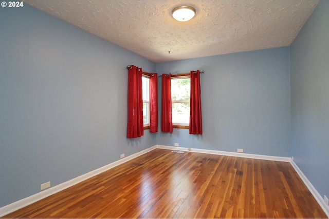 empty room with hardwood / wood-style floors and a textured ceiling