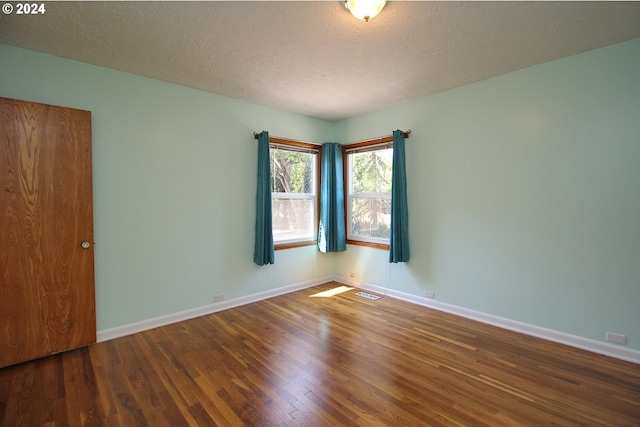 spare room featuring a textured ceiling and dark hardwood / wood-style floors