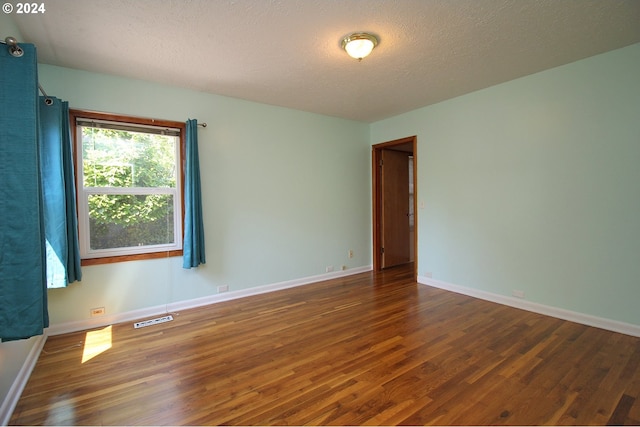 unfurnished room featuring a textured ceiling and dark wood-type flooring