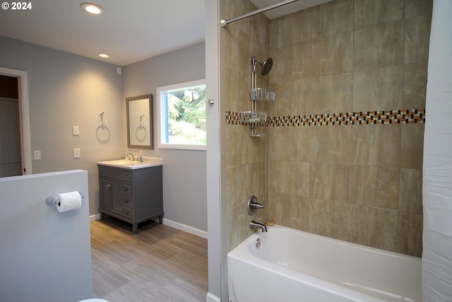 bathroom with hardwood / wood-style floors, vanity, and tiled shower / bath