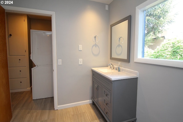 bathroom with vanity, a wealth of natural light, and stacked washer and clothes dryer