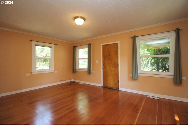 spare room featuring hardwood / wood-style flooring, ornamental molding, and a textured ceiling