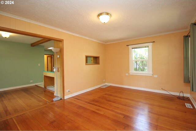 empty room with hardwood / wood-style floors, ornamental molding, and a textured ceiling