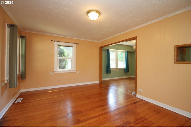 spare room with a textured ceiling, hardwood / wood-style flooring, and ornamental molding