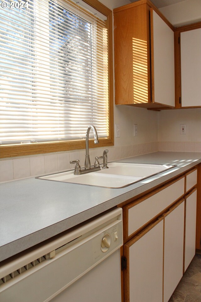 kitchen with dishwasher, plenty of natural light, white cabinets, and sink