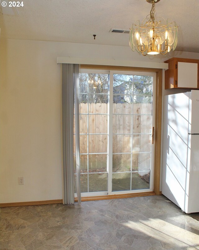 doorway to outside with a chandelier and a textured ceiling