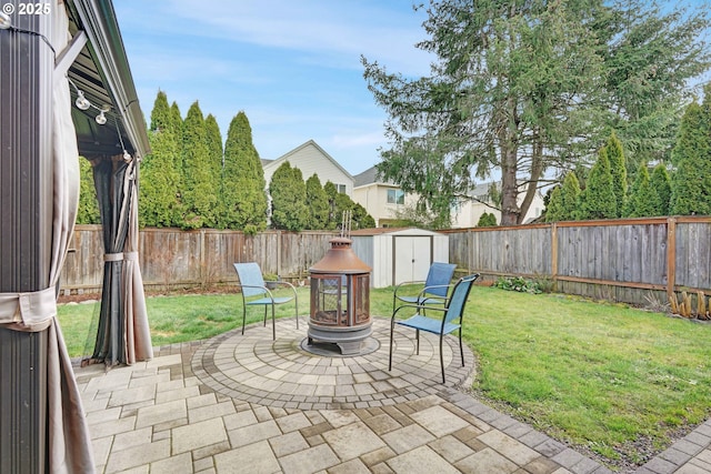 view of patio / terrace with an outdoor fire pit, a fenced backyard, an outdoor structure, and a storage unit