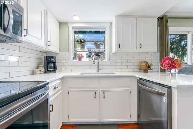 kitchen featuring stainless steel appliances, a sink, and white cabinets