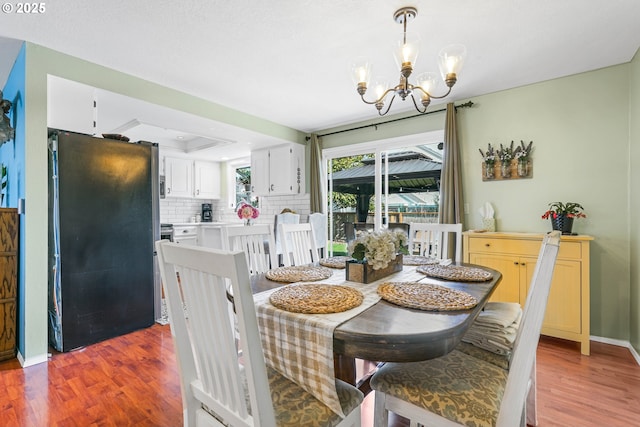 dining space with baseboards, a chandelier, and wood finished floors