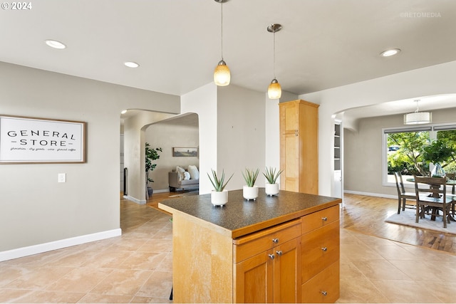 kitchen with a center island, decorative light fixtures, and light wood-type flooring