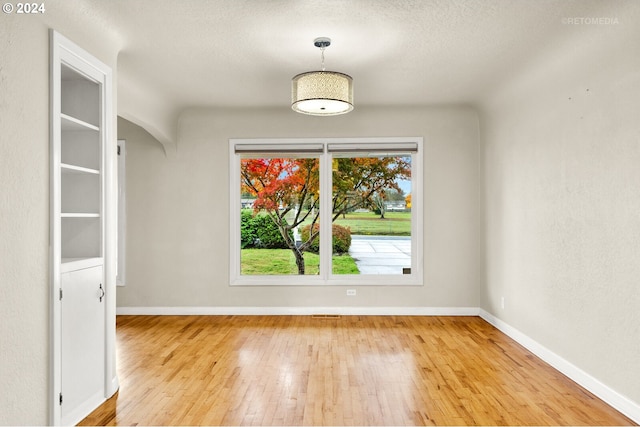 unfurnished dining area featuring a textured ceiling and light hardwood / wood-style flooring