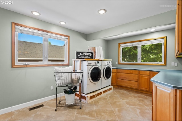 laundry room with cabinets, light tile patterned floors, separate washer and dryer, and plenty of natural light