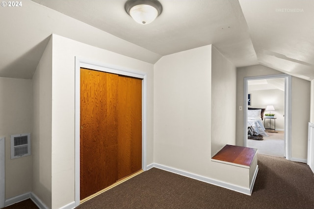 interior space featuring dark colored carpet and vaulted ceiling