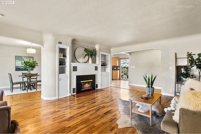 living room with hardwood / wood-style floors, a textured ceiling, and built in features