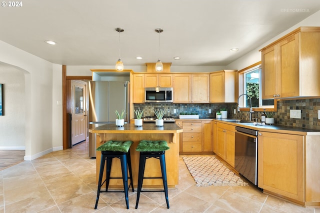 kitchen featuring light brown cabinetry, a center island, stainless steel appliances, and sink