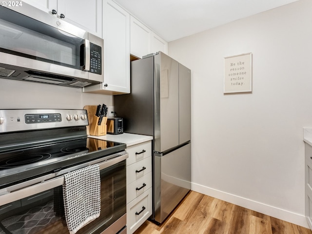 kitchen with white cabinets, appliances with stainless steel finishes, and light hardwood / wood-style flooring