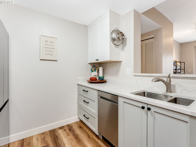 kitchen with stainless steel dishwasher, sink, white cabinetry, and light hardwood / wood-style floors