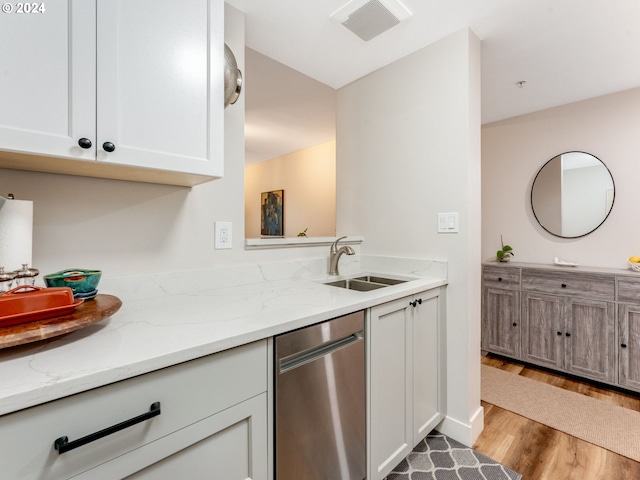 kitchen with light wood-type flooring, white cabinetry, light stone counters, and sink