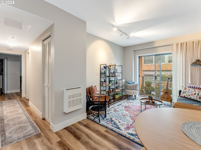 sitting room featuring rail lighting, light hardwood / wood-style floors, and heating unit