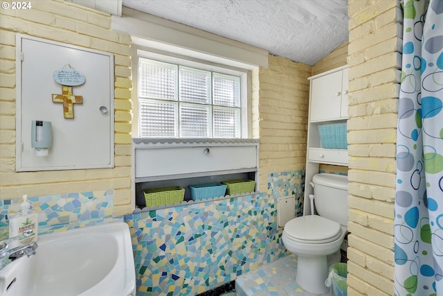 bathroom featuring a textured ceiling, toilet, sink, and vaulted ceiling