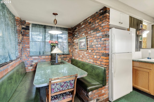 dining room with sink, breakfast area, brick wall, and dark carpet