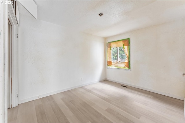 spare room featuring a textured ceiling and light wood-type flooring