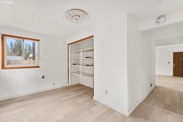 spare room with light hardwood / wood-style flooring and a textured ceiling