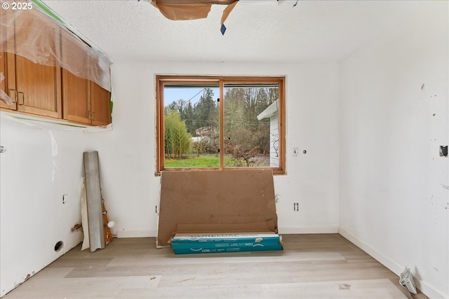 unfurnished room with light hardwood / wood-style flooring and a textured ceiling