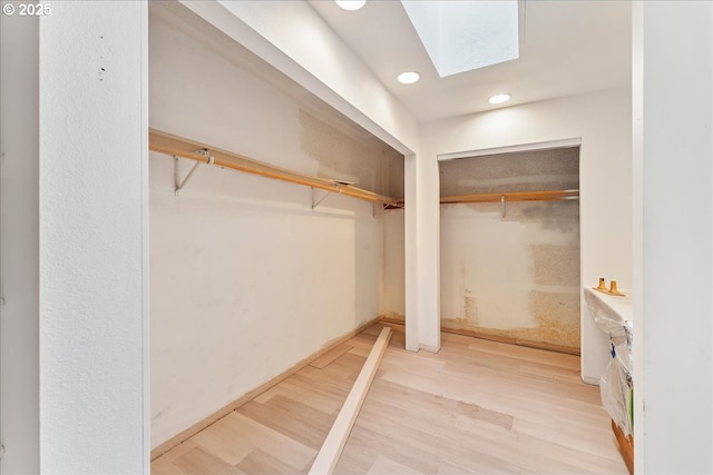 walk in closet with a skylight and light hardwood / wood-style flooring