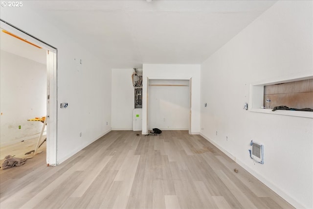 unfurnished living room featuring heating unit and light hardwood / wood-style flooring