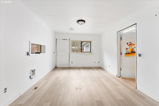 unfurnished room featuring heating unit and light hardwood / wood-style flooring