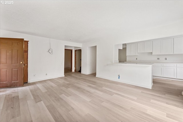 unfurnished living room with light hardwood / wood-style floors and a textured ceiling