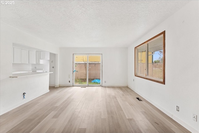 unfurnished living room with a textured ceiling and light hardwood / wood-style floors