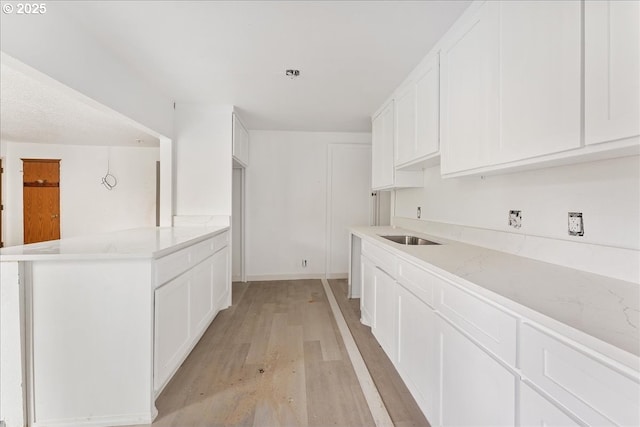 kitchen with sink, light hardwood / wood-style floors, and white cabinets