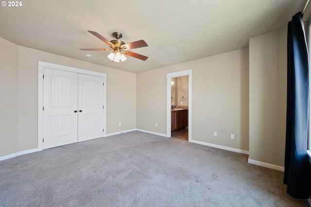 unfurnished bedroom with connected bathroom, carpet flooring, a closet, and ceiling fan