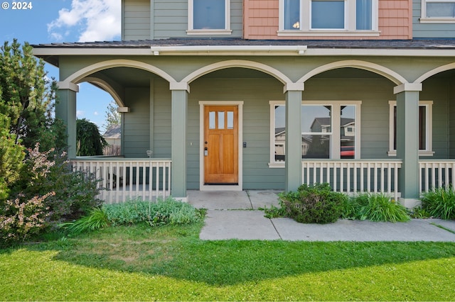 property entrance featuring a lawn and covered porch