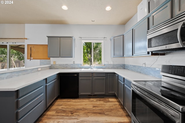 kitchen featuring appliances with stainless steel finishes, gray cabinets, sink, and light hardwood / wood-style floors