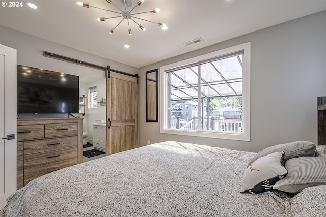 bedroom featuring a barn door, ensuite bathroom, and an inviting chandelier