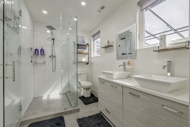 bathroom featuring vanity, tile patterned floors, toilet, a healthy amount of sunlight, and a shower with shower door