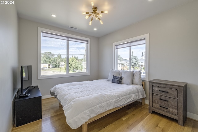 bedroom featuring an inviting chandelier and light wood-type flooring