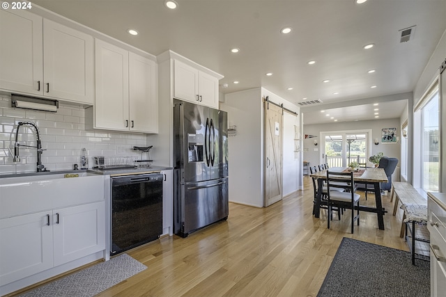 kitchen with dishwasher, stainless steel refrigerator with ice dispenser, a barn door, tasteful backsplash, and white cabinetry