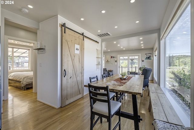 dining space with a barn door and light hardwood / wood-style flooring