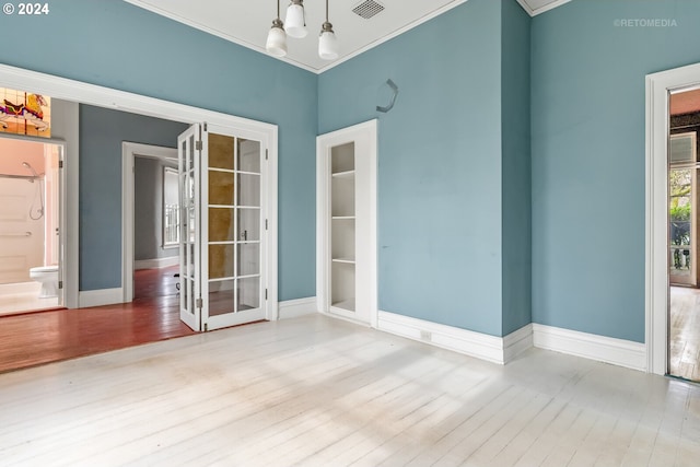 unfurnished room with ornamental molding, light wood-type flooring, and an inviting chandelier