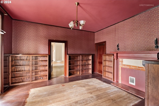 unfurnished room featuring built in shelves, dark hardwood / wood-style floors, and a chandelier