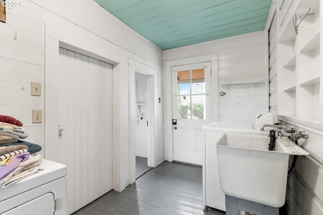 bathroom with wooden ceiling, hardwood / wood-style flooring, washer and dryer, wooden walls, and sink