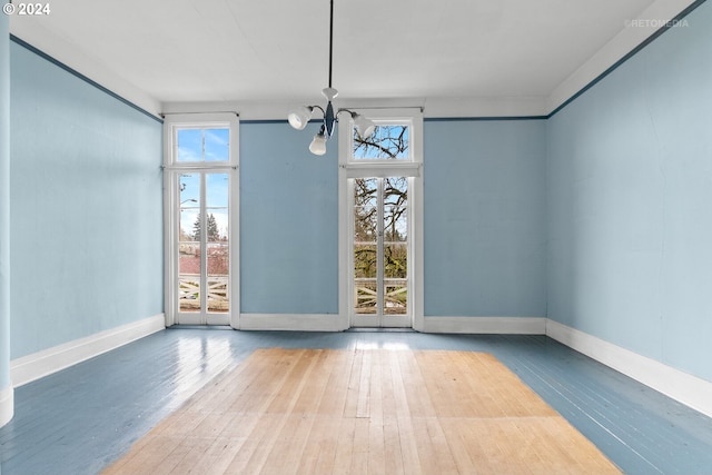 spare room featuring a chandelier, a wealth of natural light, and light wood-type flooring