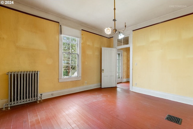 unfurnished room featuring a chandelier, dark wood-type flooring, crown molding, and radiator heating unit