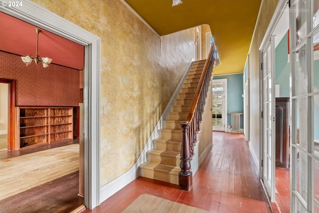 staircase with a notable chandelier, crown molding, and light hardwood / wood-style flooring