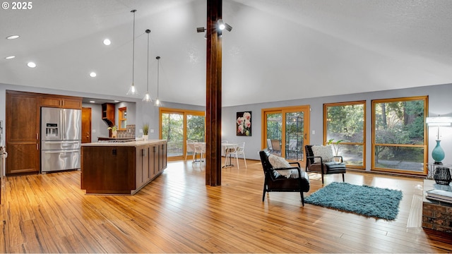 kitchen featuring stainless steel fridge with ice dispenser, decorative light fixtures, a kitchen island, and vaulted ceiling